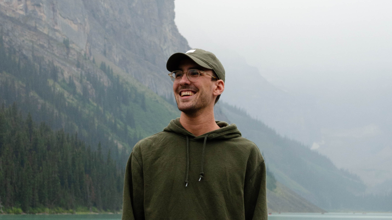 Reagan smiling big looking slightly off camera, standing in front of Lake Louise in Banff National Park, Alberta, Canada.